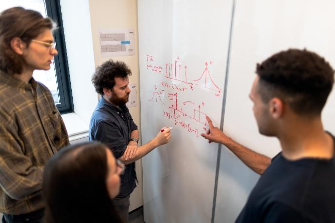 man in black crew neck t-shirt writing on white board